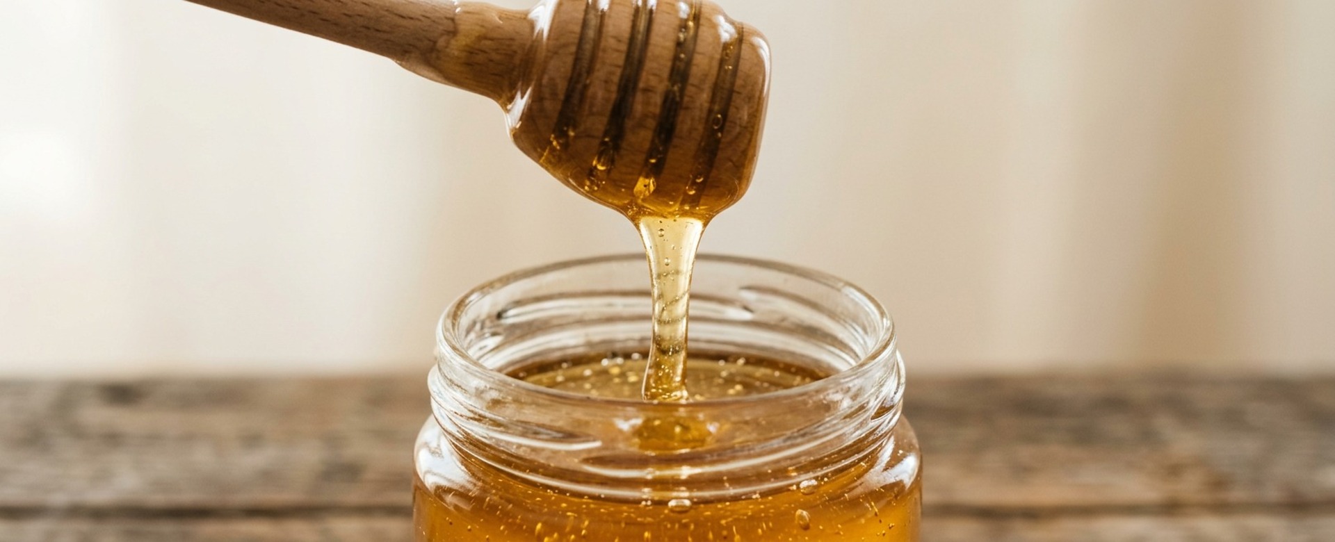 Honey dipper into a glass jar, close-up